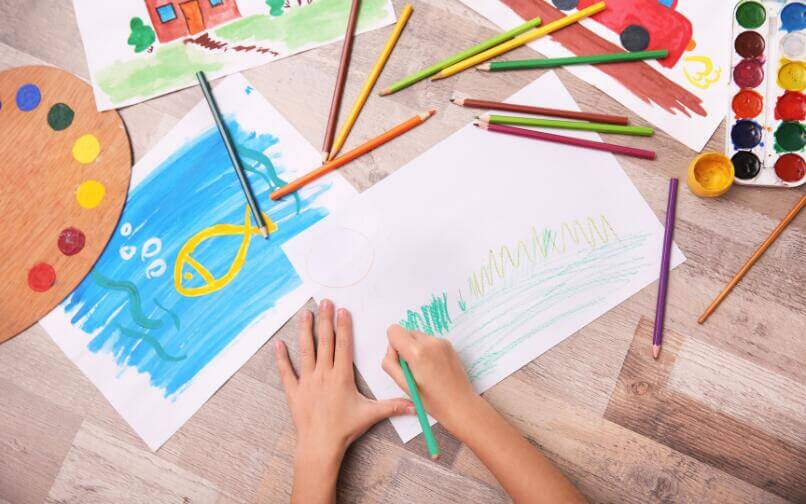 Child coloring at a table, engaging in a calming and creative summer activity.