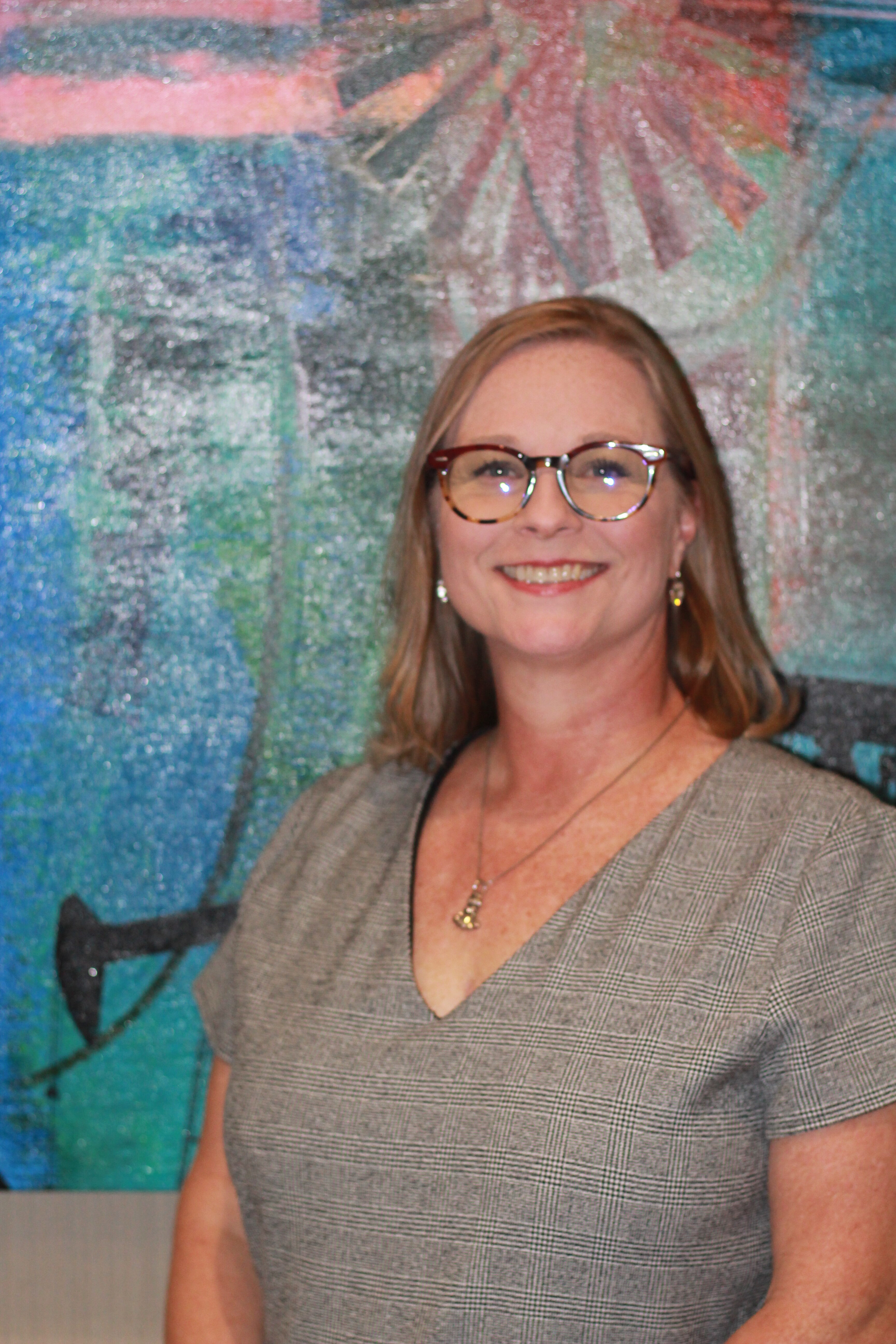 Woman with glasses smiling at a camera
